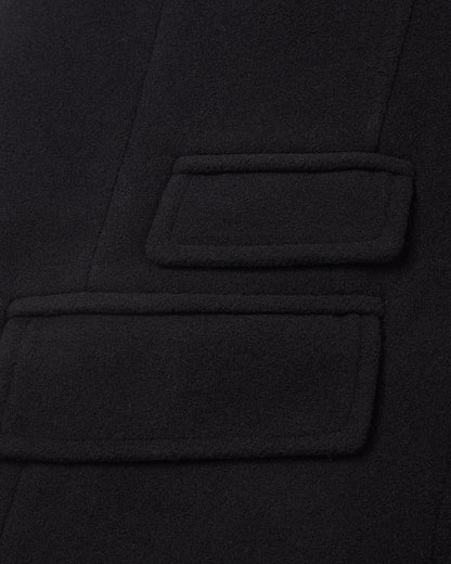 Detail of the double welt flap pockets on the black covert overcoat