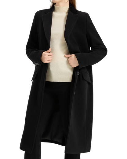Model wearing the black covert overcoat open over a cream roll-neck